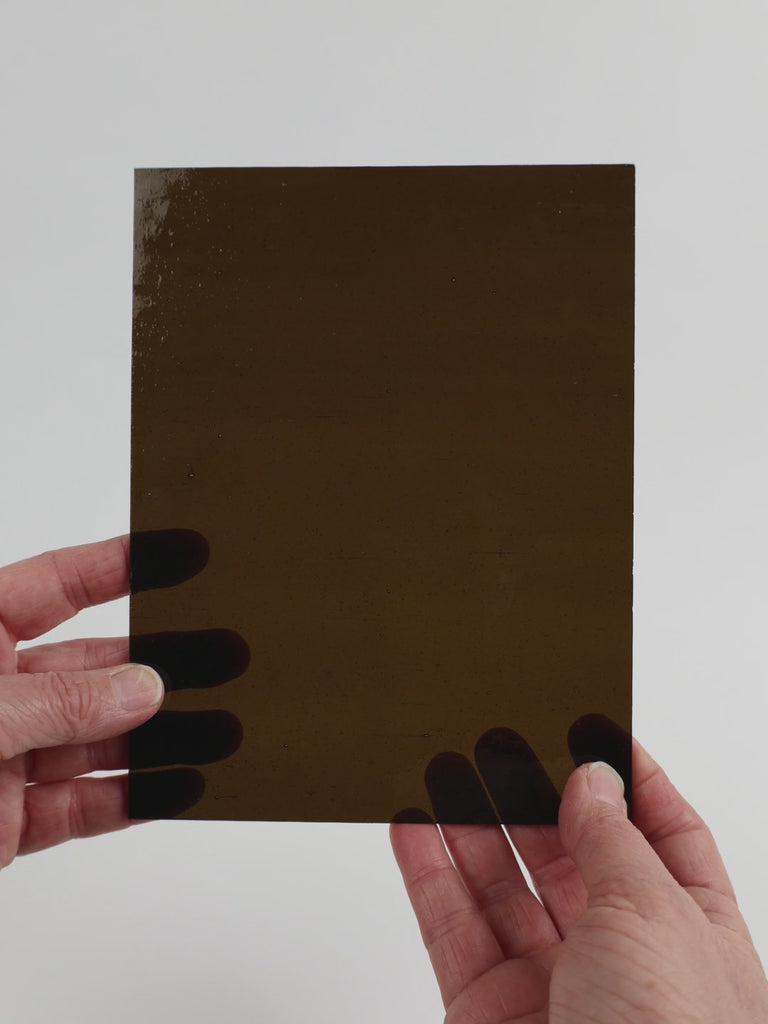 Video of the deep khaki glass plate in brown transparant, 15x19cm, held up and tilted to show its pattern and transparency